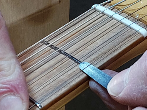 The string height is checked with a feeler gauge.